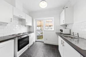 a white kitchen with a sink and a microwave at Chic Flat in Medway Comfort & Style in Chatham