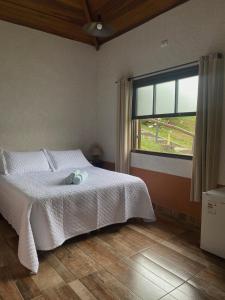 a bedroom with a white bed and a window at Estrela da Serra Hotel Fazenda in Santo Antônio do Pinhal