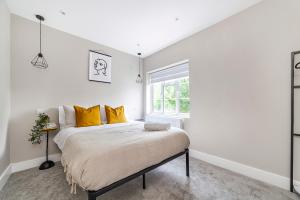 a white bedroom with a bed with yellow pillows at Arte Stays - Newly refurbish stylish 2 bedroom flat - 10 mins walk Wembley Stadium - w parking in London