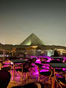 a group of tables and chairs with a pyramid in the background at MagiC Pyramids INN in Cairo