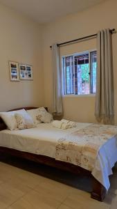 a bedroom with a large bed with a window at Casa de temporada 02 -Chalé Portal do Paraíso in Santo Amaro