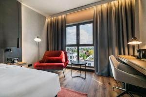 a hotel room with a bed and a chair and a window at Radisson RED Hotel & Radisson RED Apartments, Kraków in Krakow