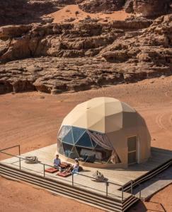 two people are sitting in a dome tent in the desert at Desert relax camp in Wadi Rum