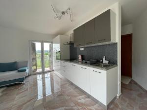 a kitchen with white cabinets and a sink at APARTMENTS GRANČIĆ in Jelsa