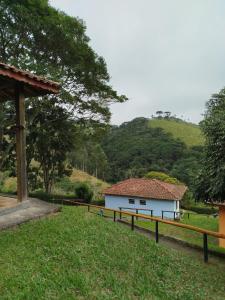 a white building in a field with a fence at Estrela da Serra Hotel Fazenda in Santo Antônio do Pinhal