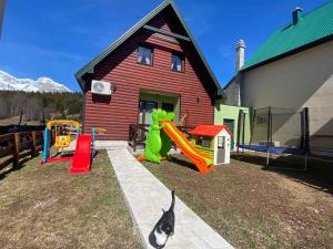 a house with playground equipment in front of a house at Holiday Homes Durmitorski Gaj in Žabljak
