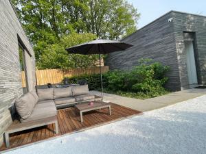 un patio con sofá y sombrilla en Tranquilo maaseik, en Maaseik