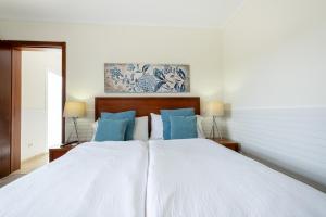a bedroom with a large white bed with blue pillows at Estalagem Pico D'Agua in Livramento