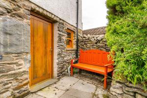 un banc rouge à côté d'un bâtiment en pierre avec une porte en bois dans l'établissement Cottontail Cottage, à Staveley