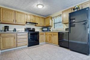 - une cuisine avec des placards en bois et un réfrigérateur noir dans l'établissement Mountain Meadows by Exploria Resorts, à Pigeon Forge