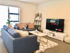 a living room with a blue couch and a tv at Fashion,Bright and Spacious,Superior location in Hamilton
