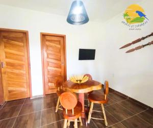 uma sala de jantar com mesa e cadeiras e uma televisão em Casa Araras de Corumbau em Corumbau