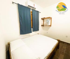 um pequeno quarto com uma cama e uma janela em Casa Araras de Corumbau em Corumbau