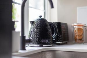 a black tea kettle sitting on a kitchen sink at Arte Stays - New & Spacious 2 Bedroom Flat - close by Wembley Stadium - Parking in London