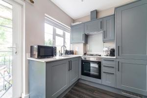 a kitchen with gray cabinets and a sink and a microwave at Arte Stays - New & Comfty 2 Bedroom Flat - 10 min walk from Wembley Stadium - w Parking in London