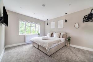 a white bedroom with a large bed and a window at Arte Stays - New & Spacious 2 Bedroom Flat - close by Wembley Stadium - Parking in London