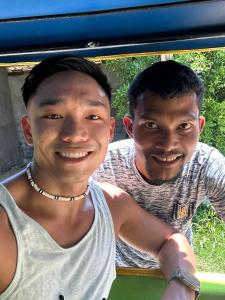 dos hombres están sonriendo mientras se sientan en un coche en navaa Bungalow, en Phra Ae beach
