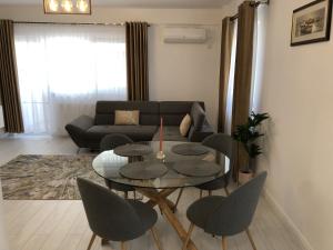 Comfort Residence Luxury Apartment في كرايوفا: غرفة معيشة مع طاولة وكراسي وأريكة