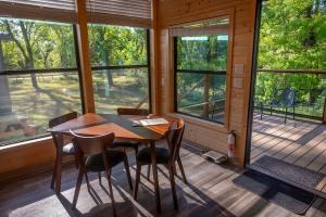 ein Esszimmer mit einem Tisch, Stühlen und Fenstern in der Unterkunft Sierra Meadows in Ahwahnee