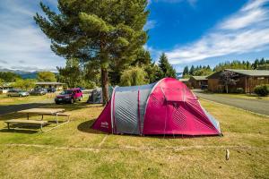 a tent and a picnic table in a field at Te Anau Lakeview Holiday Park & Motels in Te Anau