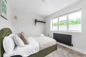 a white bedroom with a bed and a window at Arte Stays - Lux Stylish Penthouse - Heart of Wembley - Parking in London