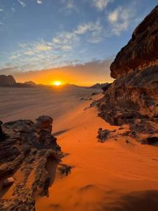 um pôr-do-sol sobre um deserto com pedras e o sol em Waid Rum Jordan Jordan em Wadi Rum