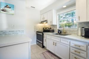 Una cocina con gabinetes blancos y un fregadero y una ventana. en Sparkling Oasis near Downtown ST Pete/Beach, en San Petersburgo 11 fotos más
