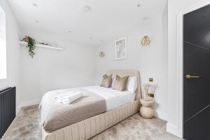 una camera da letto bianca con un letto con lenzuola e cuscini bianchi di Arte Stays - Modern and Newly refurbished Penthouse - Heart of Wembley - w private parking a Londra