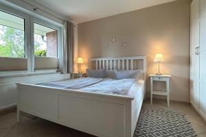 1 dormitorio con 1 cama blanca grande y ventana en Ferienwohnung-9-mit-Terrasse-Garten-Landhaus-Hubertus-Duhnen, en Cuxhaven