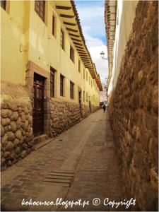 an alley with a stone building and a person walking down it at Hotel TIKA AYNA Cerca a la plaza de Armas CUSCO in Cusco