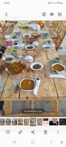 Maison d'hôte dar massouada في Tūjān: طاولة خشبية طويلة مع العديد من أطباق الطعام