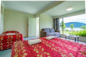 a bedroom with two beds and a couch and a window at Te Anau Lakeview Holiday Park & Motels in Te Anau