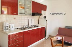 a small kitchen with red cabinets and a sink at Apartments with WiFi Lopar, Rab - 14804 in Lopar