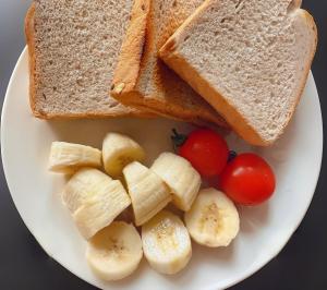 a plate with bread and bananas and tomatoes on it at Tongfu Inn(In the National Park) in Zhangjiajie