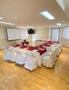 una sala conferenze con tavoli, sedie bianche e schermo di Hoteli Alifer Tlaxcala X TECAL LIVING a Tlaxcala de Xicohténcatl