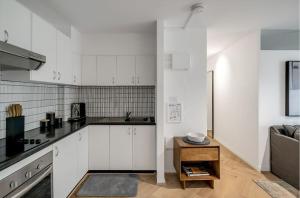 una piccola cucina con armadi bianchi e tavolo di Cosy Retreat in Bondi Junction -1BR Gem a Sydney