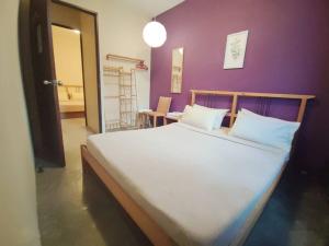 a bedroom with a large bed with a purple wall at The Cottage Stay formerly Sunset Homestay 2 in Kuching
