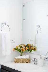 a bathroom with a sink with a mirror and flowers at CASA LOMA HOTEL BOUTIQUE & TERRAZA GASTRO in Popayan