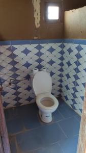 a bathroom with a toilet with blue and white tiles at Camp & Trek in Mhamid