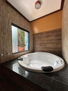 La salle de bains est pourvue d'une grande baignoire blanche et d'une fenêtre. dans l'établissement Pousada Evolucao, à Macacos