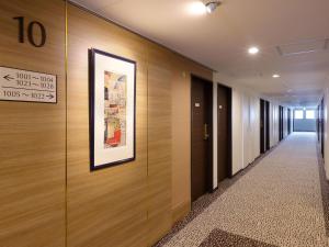 um corredor com paredes de madeira e uma imagem na parede em Keio Presso Inn Kanda em Tóquio
