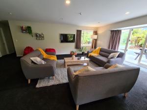 a living room with two couches and a tv at Rainforest Retreat in Franz Josef