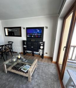 a living room with a large tv and a table at Valle Nevado Apartamento Ski In Out in Valle Nevado