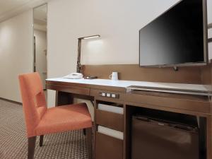 um quarto com uma secretária, uma televisão e uma cadeira em Keio Presso Inn Kanda em Tóquio