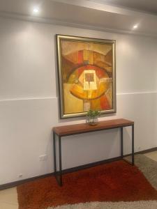 un cuadro colgado en una pared con una mesa en Hospedaje en Quito Norte, Apartamento & Suite independientes en Quito