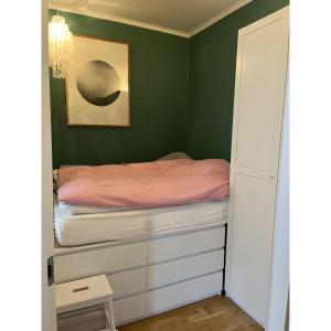 哥本哈根的住宿－ApartmentInCopenhagen Apartment 43，一间拥有绿色墙壁的卧室和一张配有粉红色床单的床