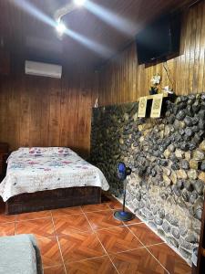 a bedroom with a bed and a stone wall at Mochileros MarAbi in Tarcoles