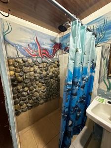 ein Bad mit einer Dusche und einem Wandgemälde in der Unterkunft Mochileros MarAbi in Tarcoles