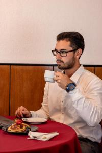 um homem sentado à mesa a beber uma chávena de café em Hotel America Chiclayo em Chiclayo