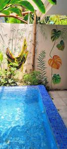 a pool with a hammock and a wall with a mural at Mecca in Puerto Viejo